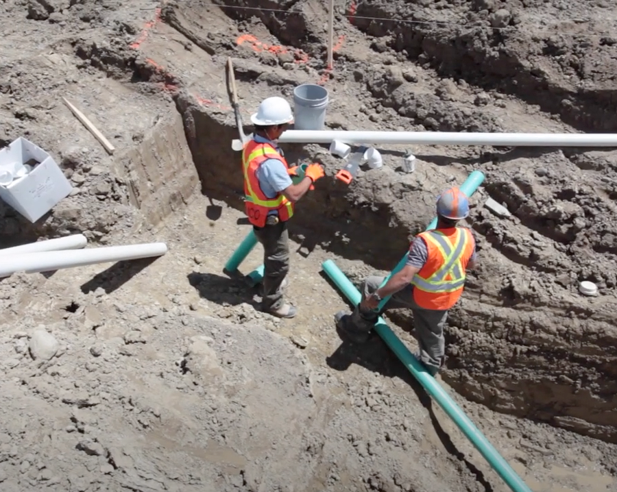 Image of a person working on a drainage pipe.